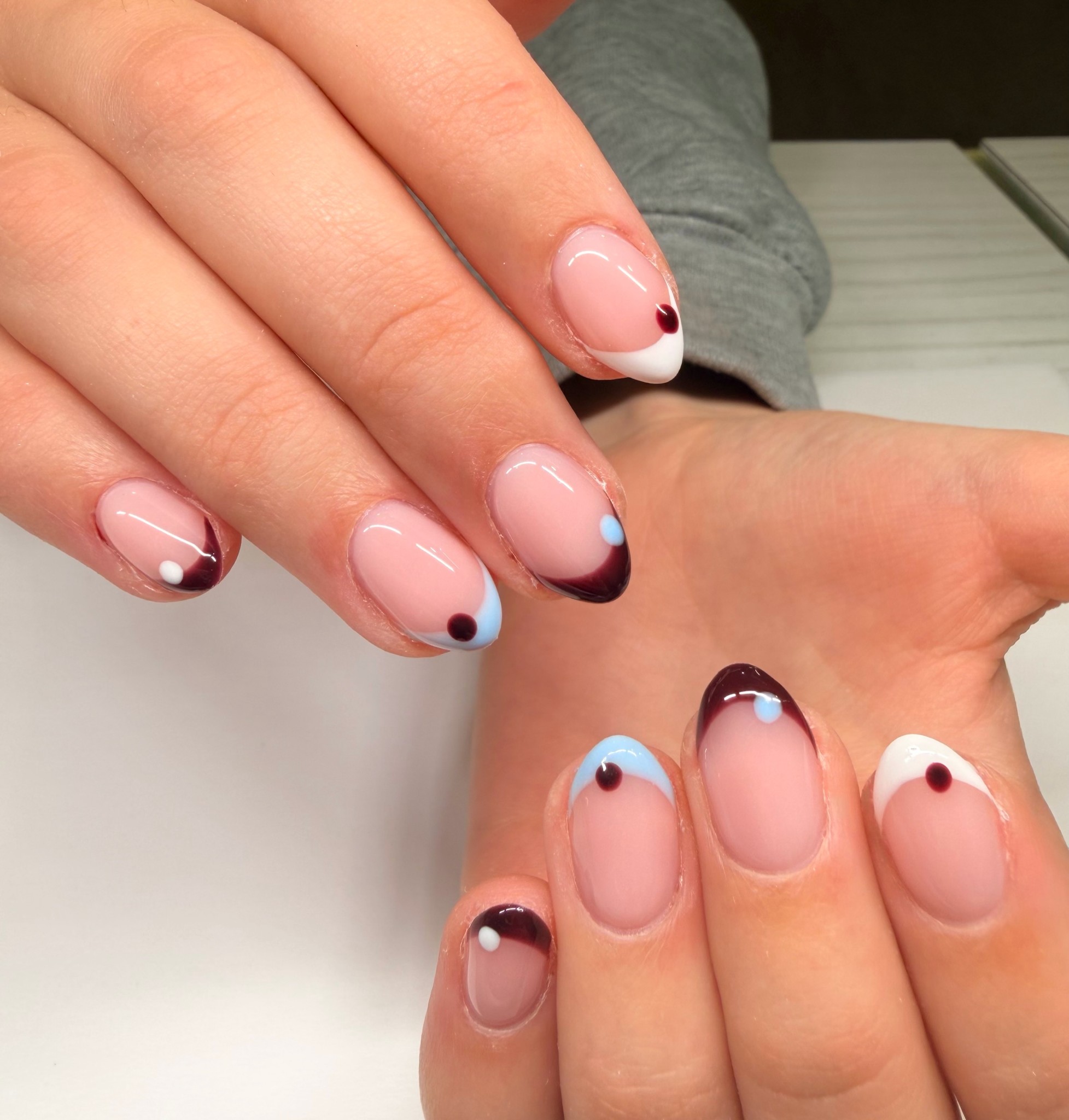 French tip nails with a little twist: nude base with white, brown and pale blue tips and a dot of colour