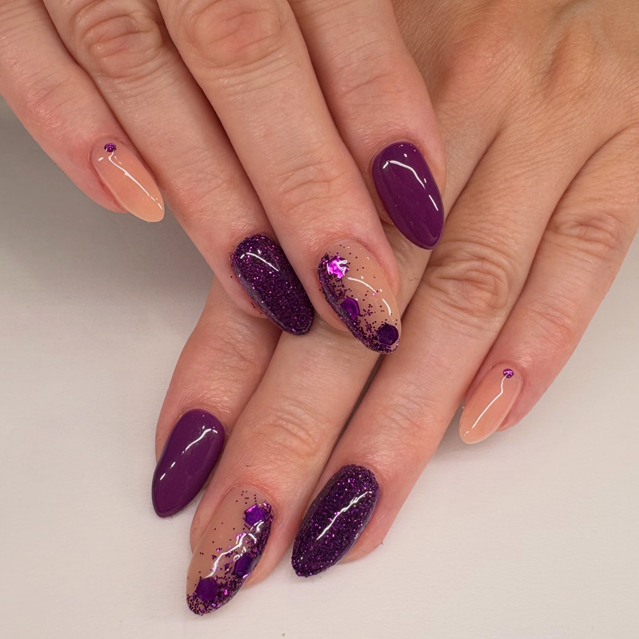 Almond nails in aubergine purple with glitter and gem nail art